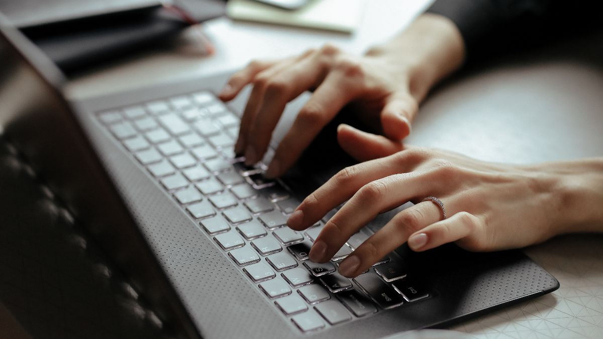 Imagem de uma pessoa, com suas mãos, digitando possivelmente alguma informação ao registrar domínio
